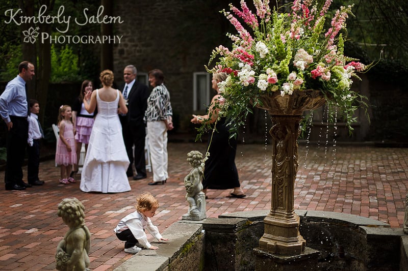 Ring bearer checks out the wishing well while the bride chats in the background