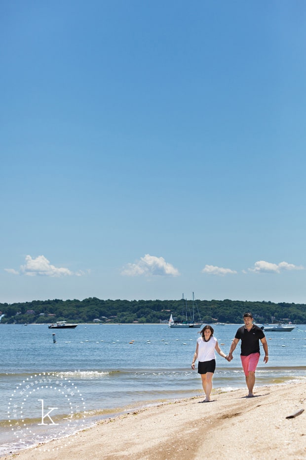 engaged couple walking along beach