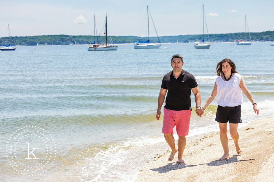 engaged couple walking along beach - horizontal