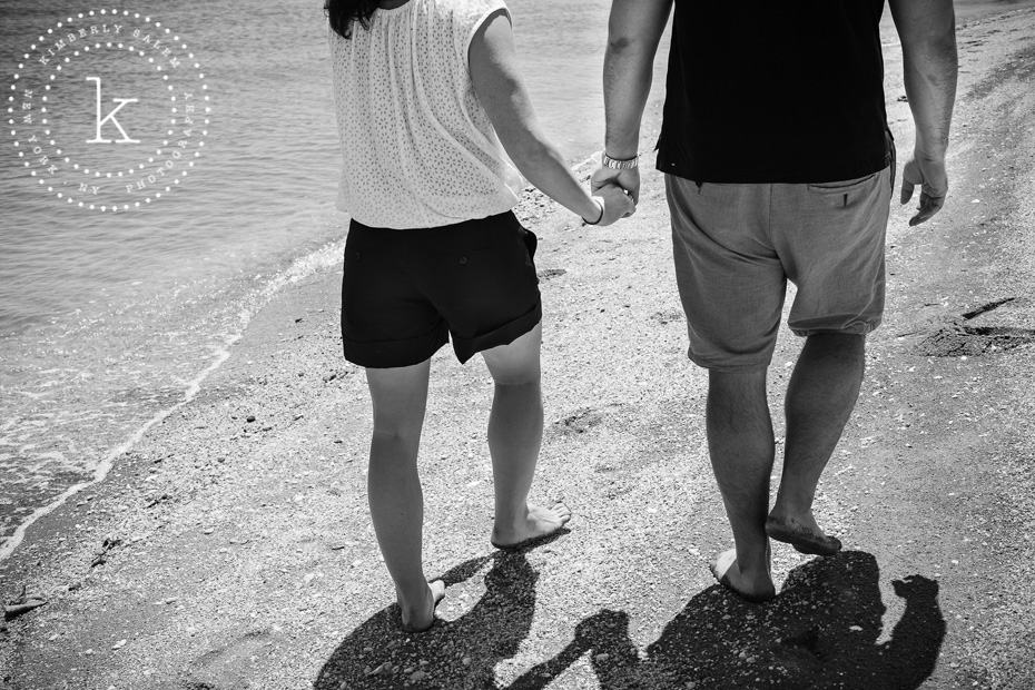 engaged couple holding hands at beach - black & white