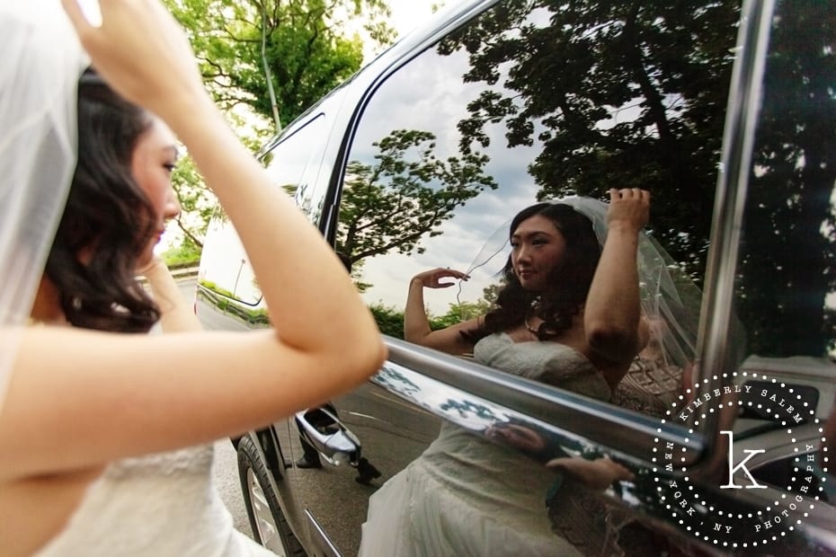 bride fixing her veil in car reflection