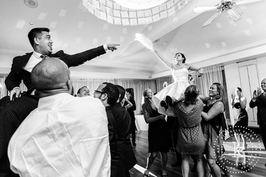 Bride and groom on chairs during the Hora - holding up cloth