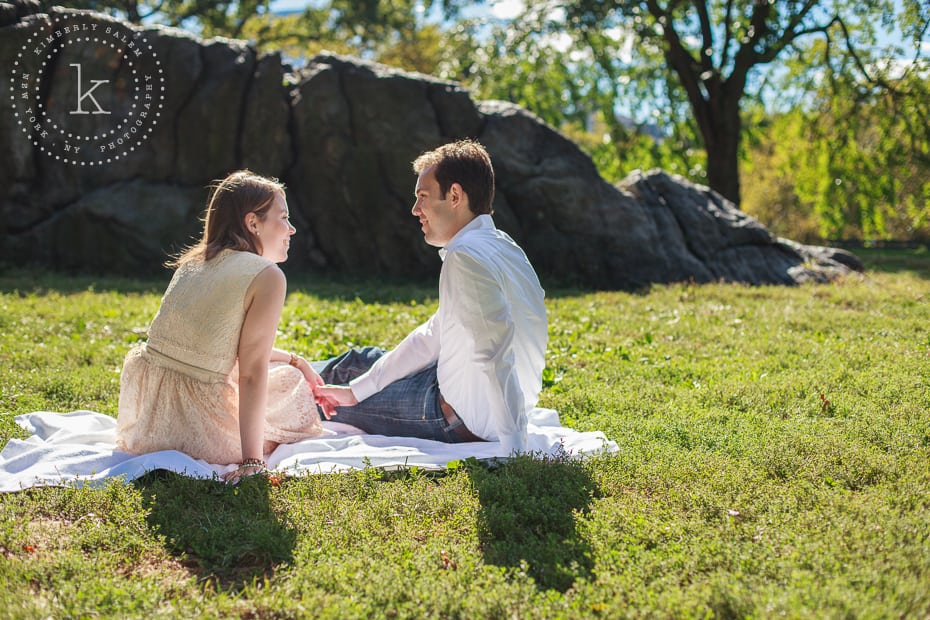 engaged couple sitting by a rock in central park