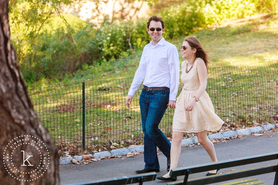 engaged couple wearing sunglasses and walking in central park