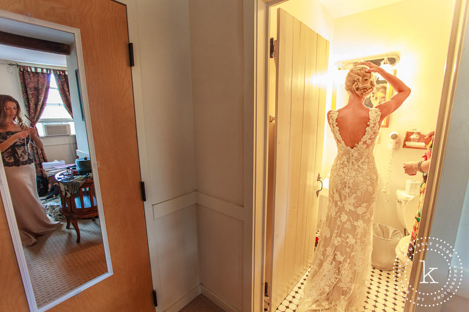 Bride fixing her hair, bridesmaid in the outer room