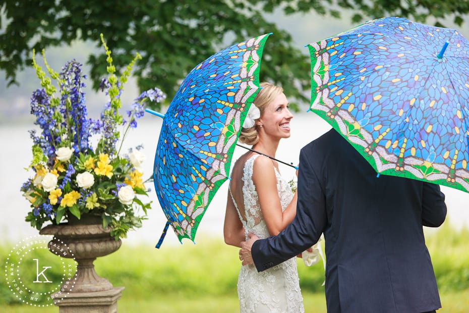 Bride looks at groom under blue umbrellas