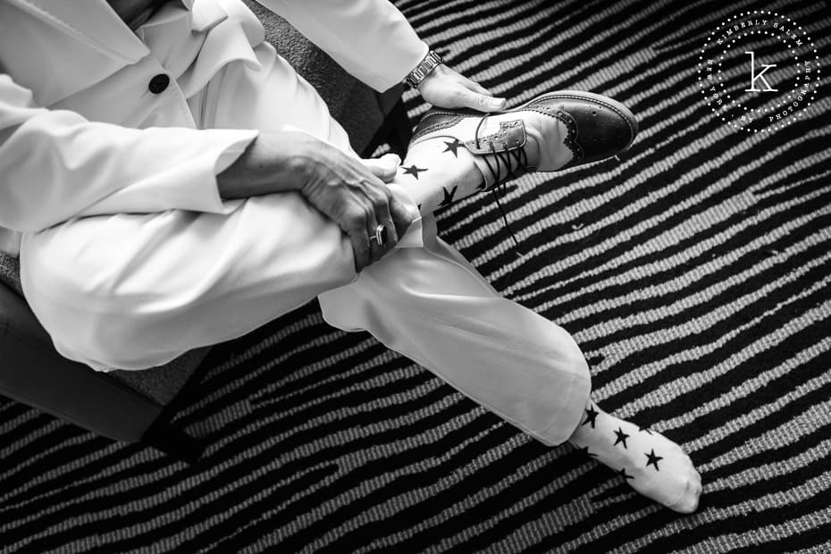 bride putting on her black and white oxfords