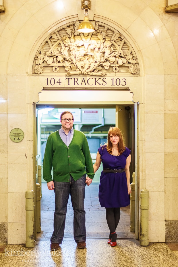 engaged couple by train track entrance in Grand Central