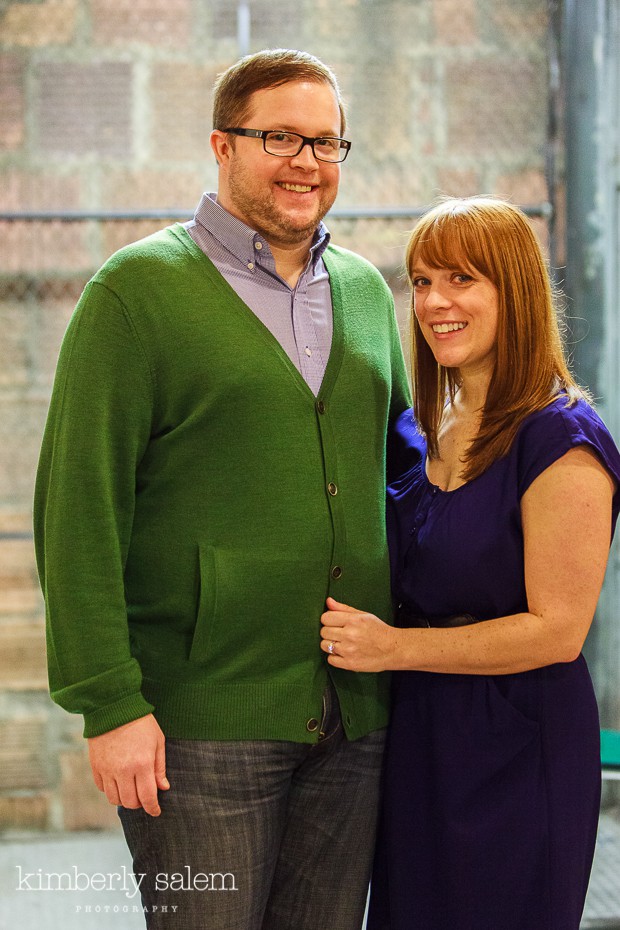 engaged couple with brick and chain link background