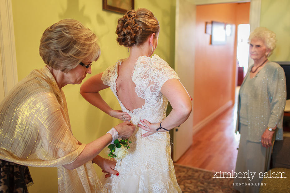 bride getting her dress zipped by her mother