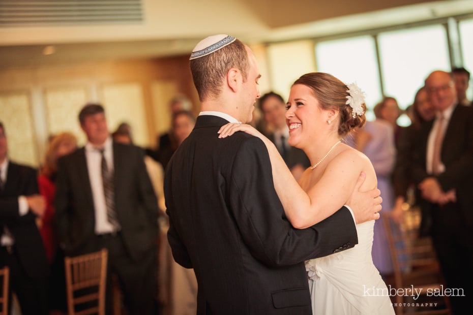 bride and groom first dance with guests in background