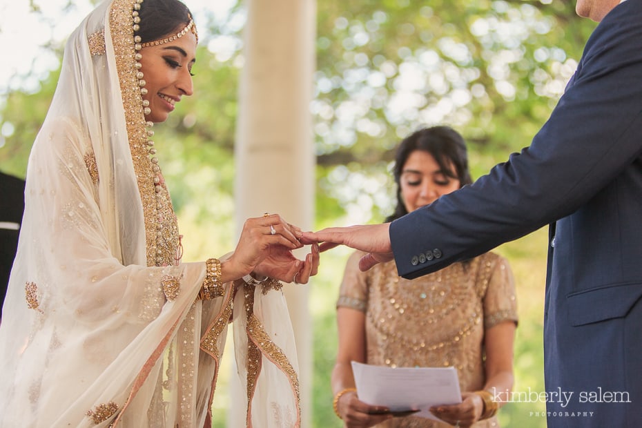 bride puts ring on groom's finger during wedding ceremony in Prospect Park Peristyle