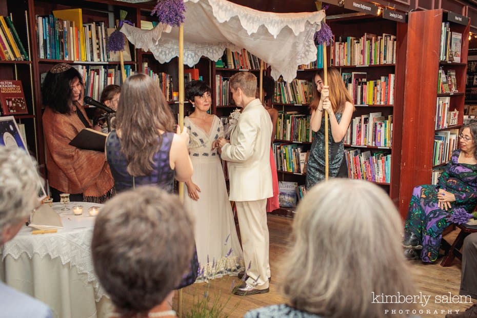 Brides getting married in bookstore under the chuppah