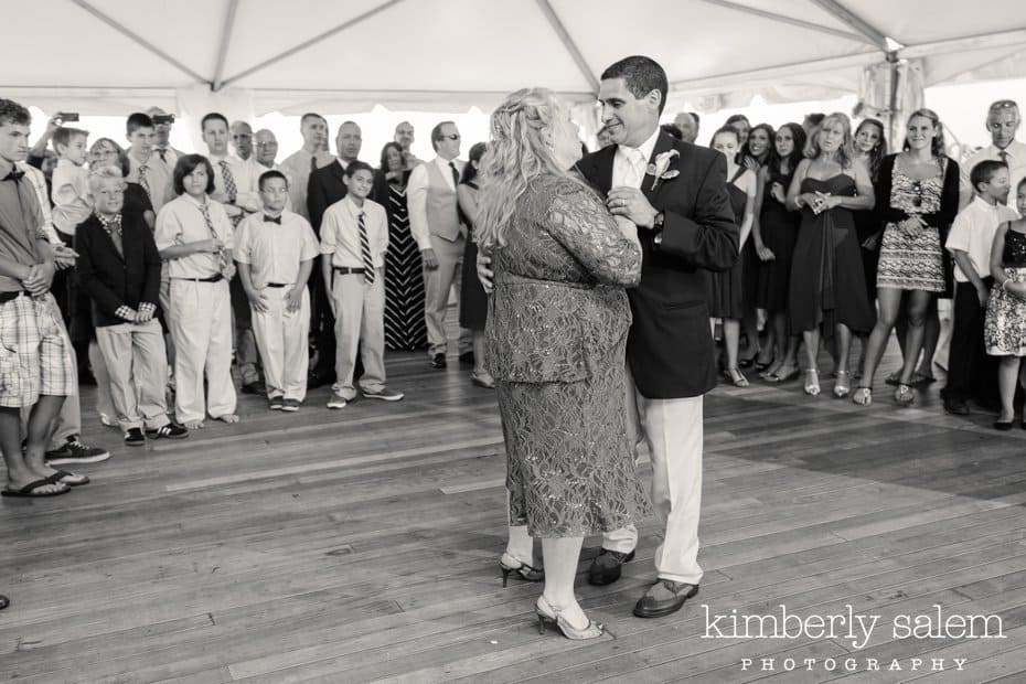 bride and groom first dance with guests looking on