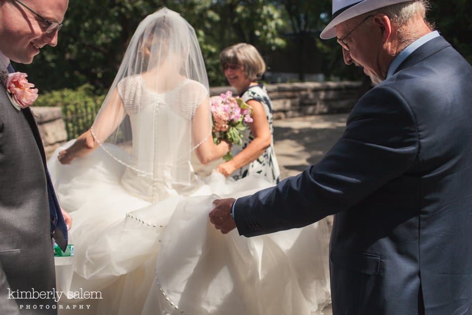 Candid shot of family helping the bride with her dress