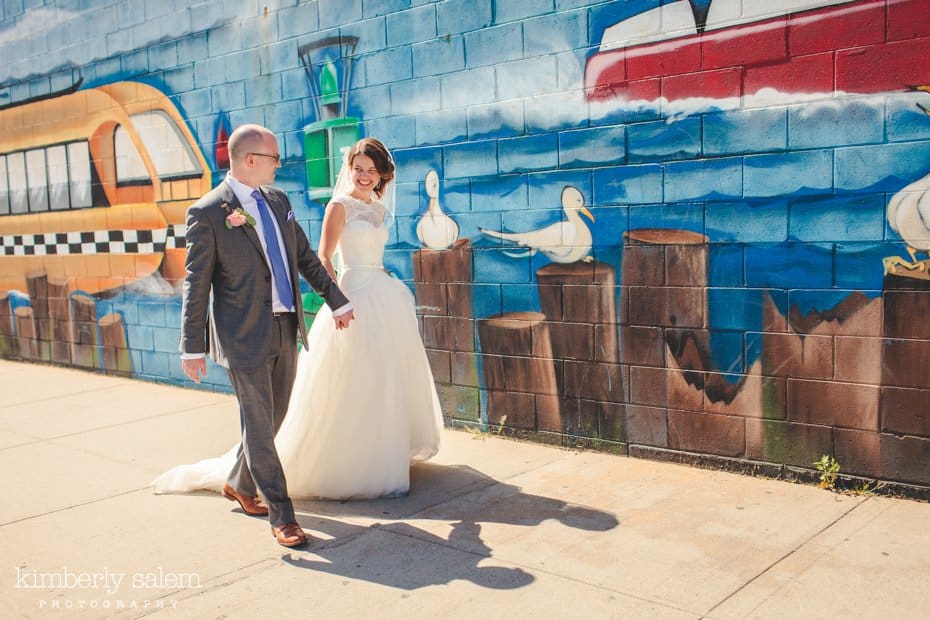 Bride and groom walk in front of a painted mural in Williamsburg, Brooklyn